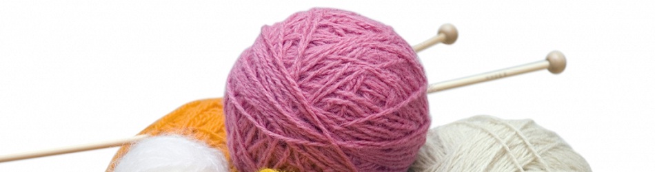 Sticking to the knitting - a ball of pink wool with knitting needles jabbed into it with balls of white and yellow wool in front and behind