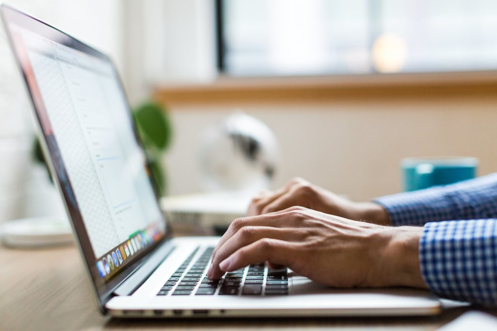 Slow Wi-Fi - side view of a laptop on a desk with male hands typing.