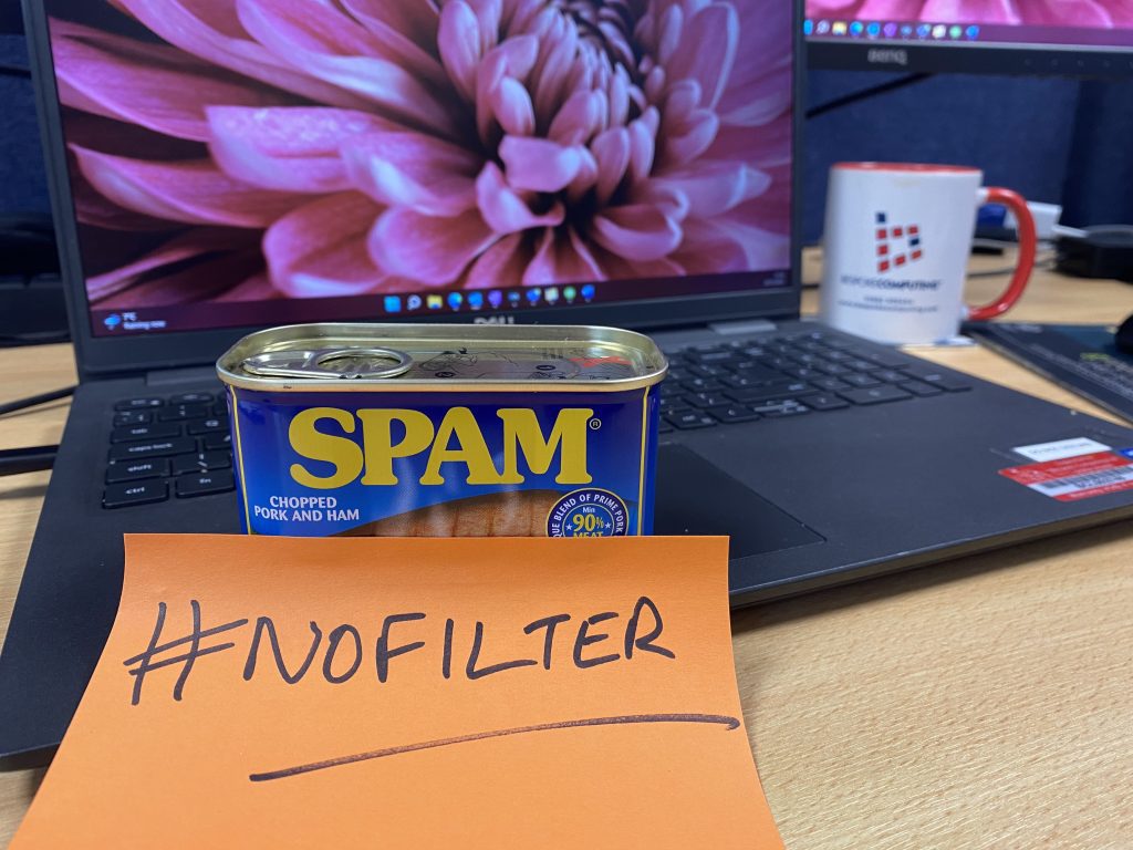 Email Spam Filter - image of a laptop with large screen in background and in the foreground is a tin of Spam with a post-it note attached with the hashtag #nofilter written on it.