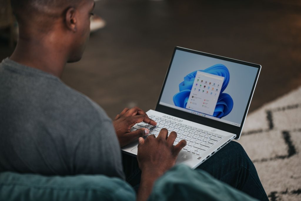 Microsoft Power BI - image of a man sitting with a laptop on his knee with Microsoft Suite icons displayed